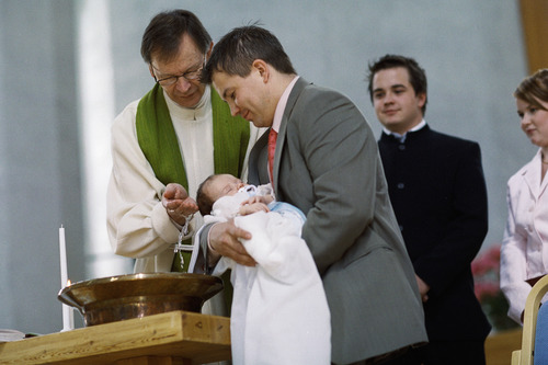 Pappi kastaa lasta, joka on mieshenkilön sylissä.