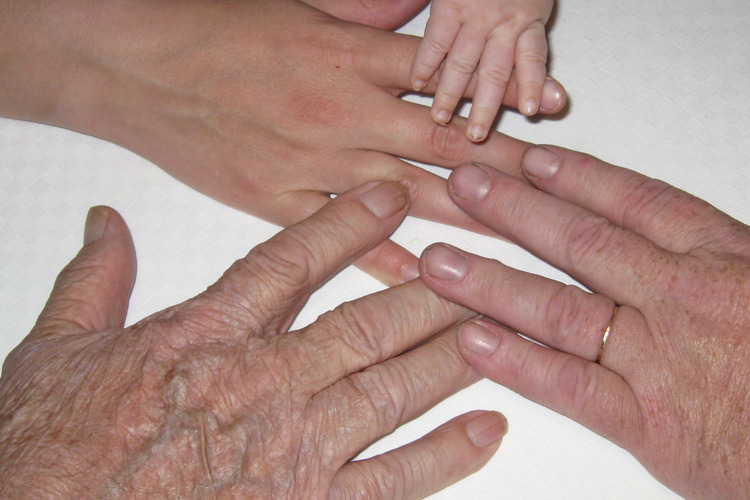 Neljän eri sukupolven erikokoiset kädet vauvasta isovanhempaan.