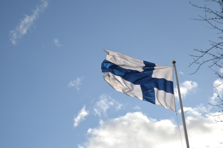 Juhannuspäivän maakirkko Heinijoen koululla Suomen lippu taivasta vasten kuvattuna.