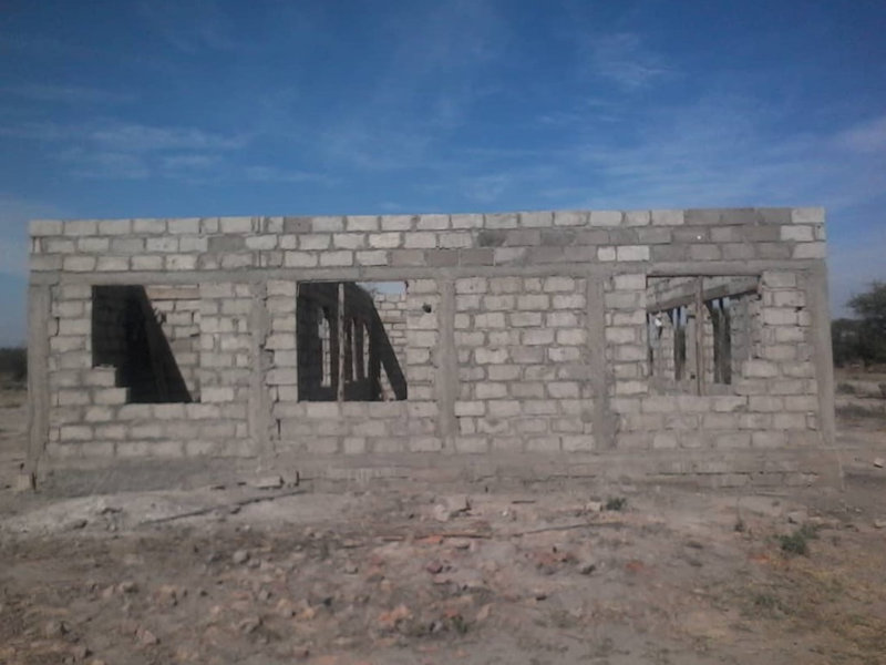 Kirkon rakennustyömaalta Tansaniasta. Tiiliseinää sivulta. Kattoa ei vielä ole ja ikkunalasit puuttuvat.